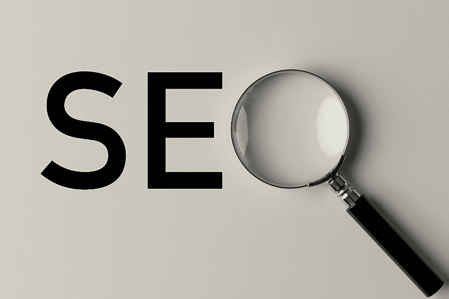 A magnifying glass focuses on the letters "seo" printed in bold, black type on a light gray background.