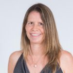 Smiling woman in a sleeveless top with long brown hair against a white background.