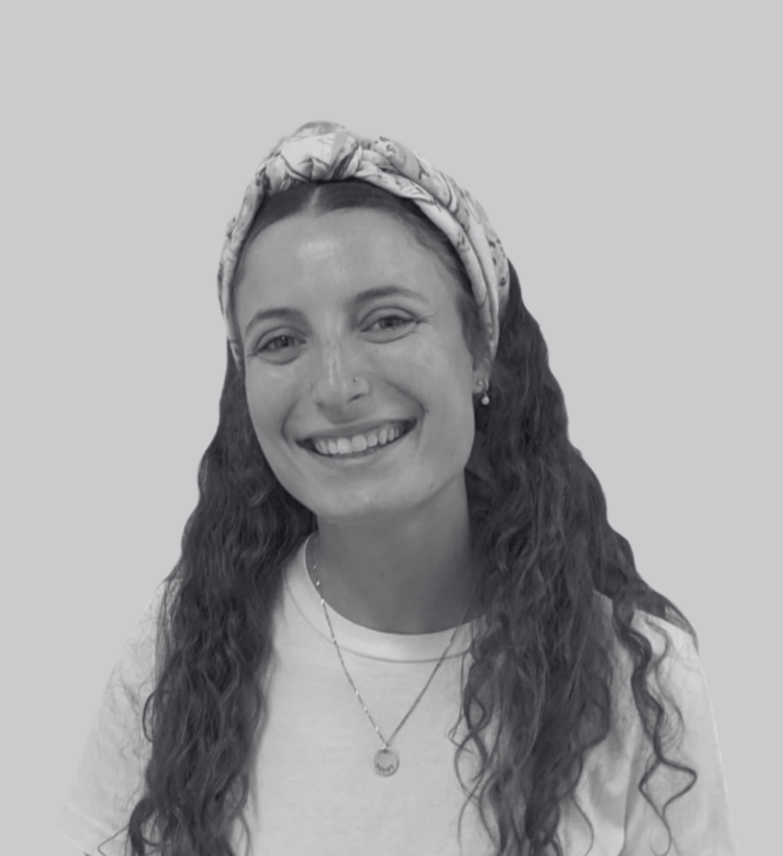 Smiling woman with long curly hair, wearing a headband and necklace, in grayscale.