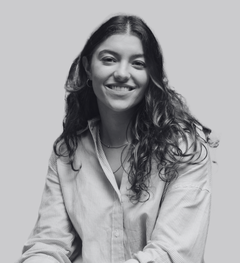 Woman smiling, wearing a striped shirt, with curly hair against a plain background.