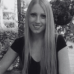 A woman with long hair smiling while seated outside.