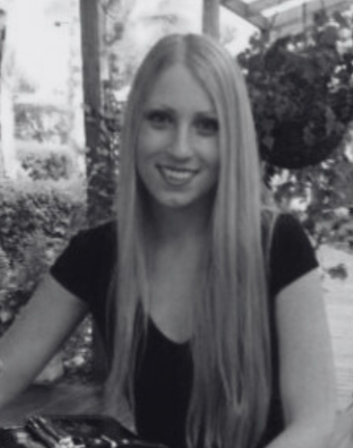 A woman with long hair smiling while seated outside.