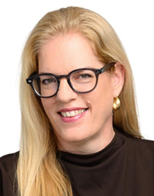 Woman with long blonde hair, glasses, gold earring, and a black top, smiling at camera.