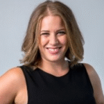 Woman with shoulder-length light brown hair smiles, wearing a sleeveless black top.