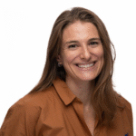 Woman with long brown hair smiling, wearing a brown shirt, on a white background.