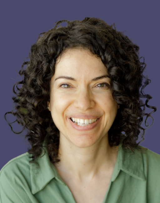 Smiling woman with curly hair wearing a green shirt on a solid purple background.