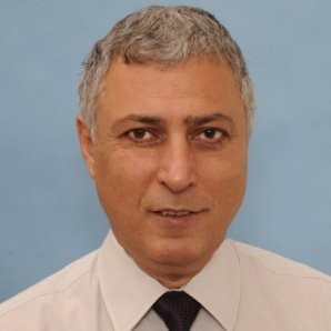 Middle-aged man with short gray hair in a white shirt and dark tie, against blue background.